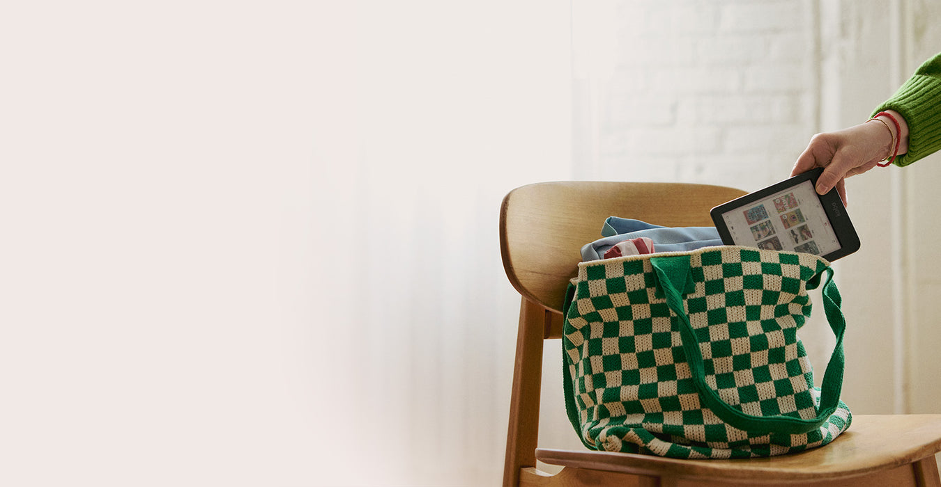 A hand removes a Kobo Clara Colour eReader from a bookbag sitting on a wooden chair.