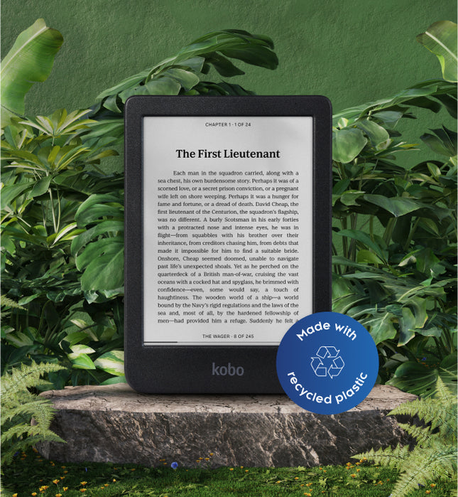 A Kobo Clara BW eReader with a label that reads "Made with recycled plastic". set on a stone in foliage.